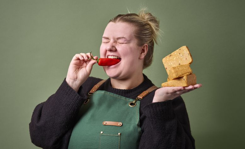 Woman with a block of cheese biting a chilli